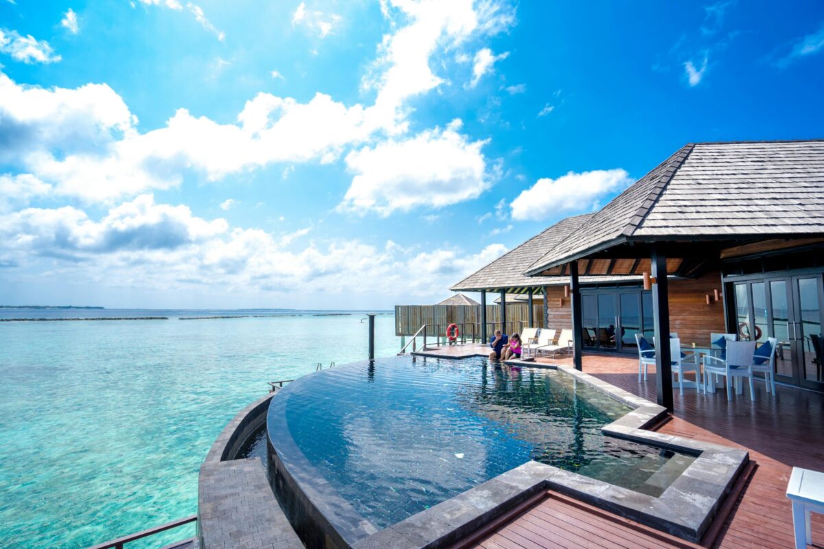 Stunning tropical villa by the sea with an infinity pool under clear blue sky.